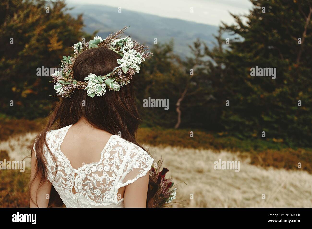 elegante sposa in posa con bouquet sullo sfondo della foresta, lussuoso boho matrimonio in montagna Foto Stock
