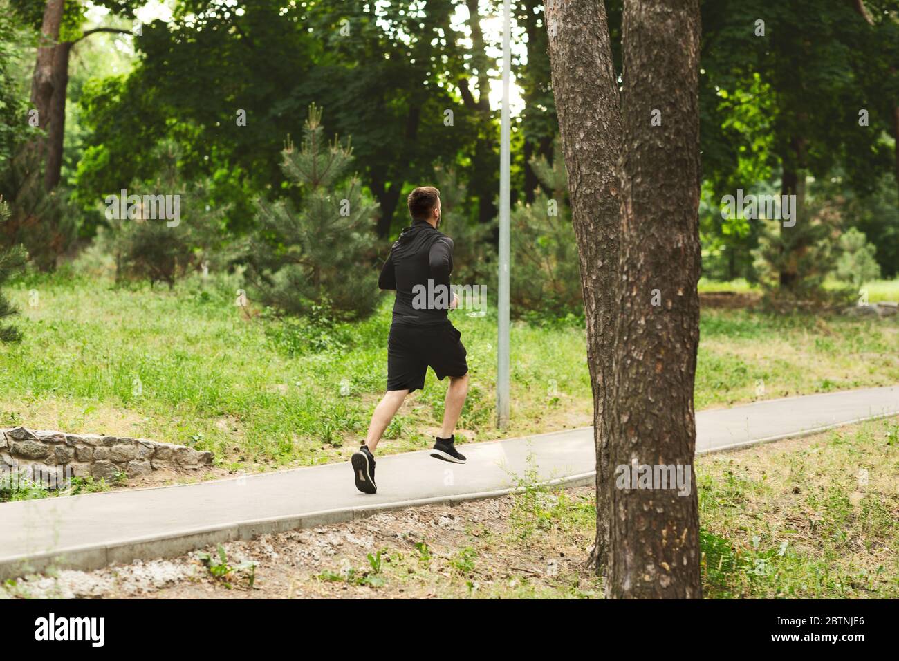 Fitness uomo sportivo che corre in pista forestale Foto Stock