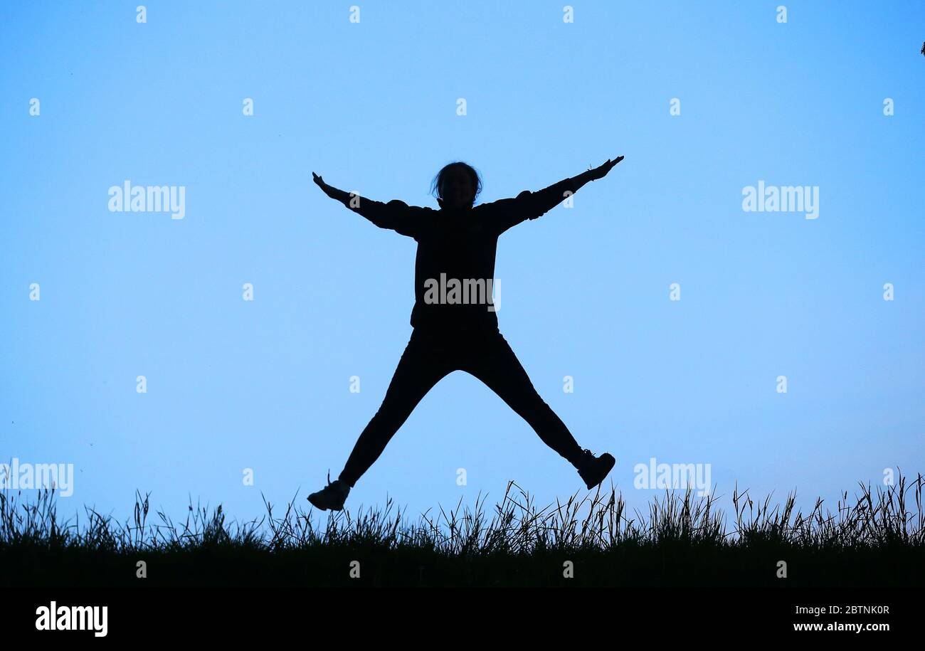 Una donna fa un salto di stella a Belfast orientale, Irlanda del Nord, sulla sua autorizzazione quotidiana di esercizio durante il blocco pandemico COVID-19. Foto Stock
