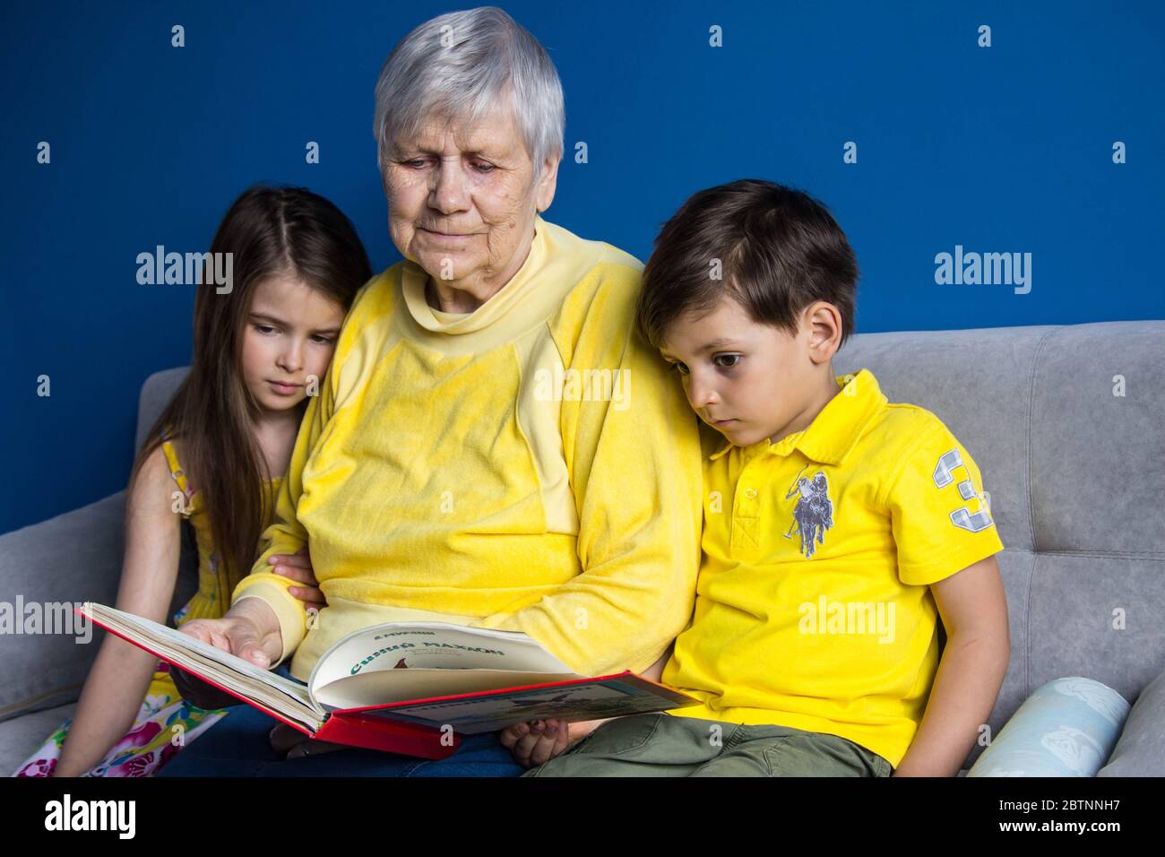 Una vecchia nonna e i suoi amati nipoti si siedono a casa e scattano foto sul loro smartphone Foto Stock