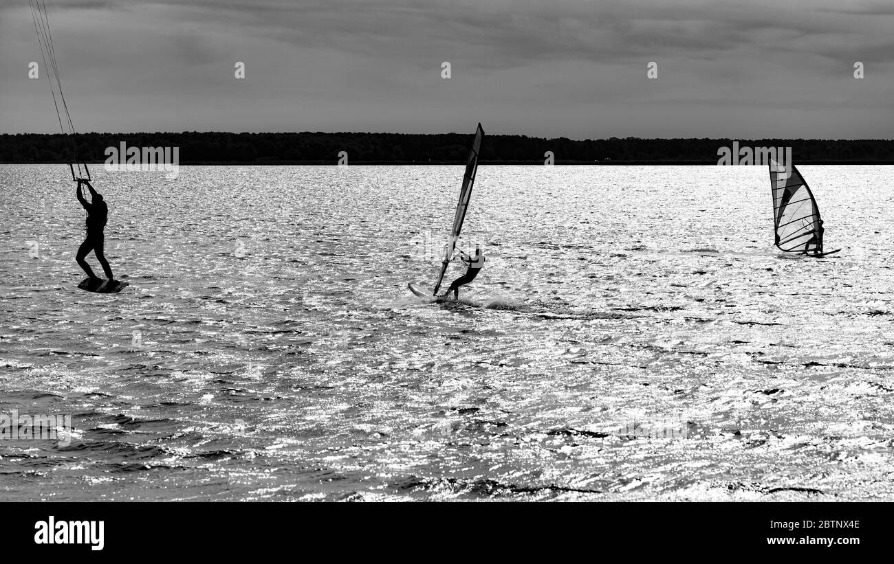 Atlete del windsurf e del kitesurf sul lago, foto in bianco e nero. Foto Stock