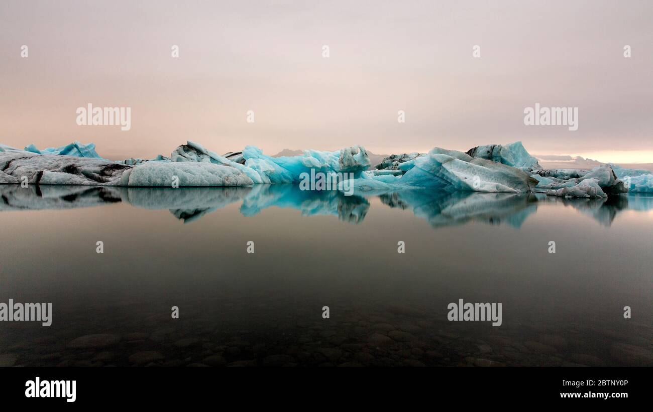 Riflesso di ghiaccio che scivola al tramonto in un mare piatto Foto Stock