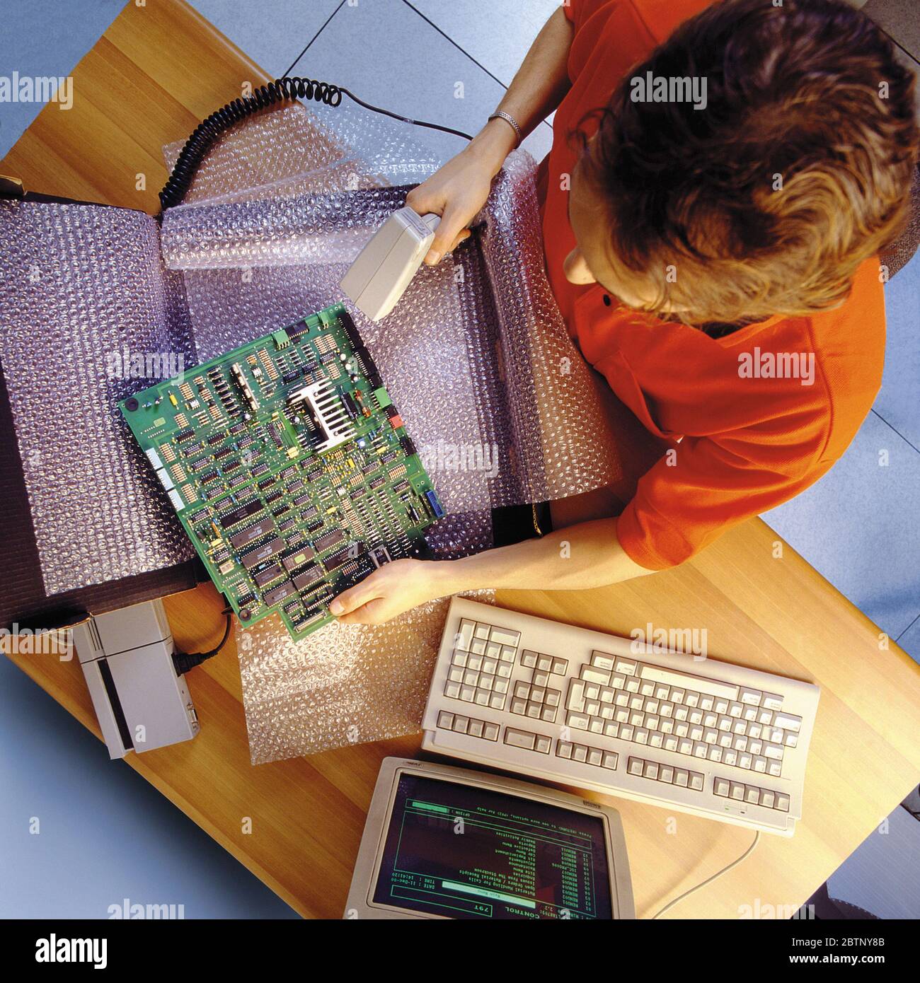 Vista dall'alto di un addetto al magazzino che codifica i componenti del computer da spedire con un lettore di barre. Foto del 1990 Foto Stock