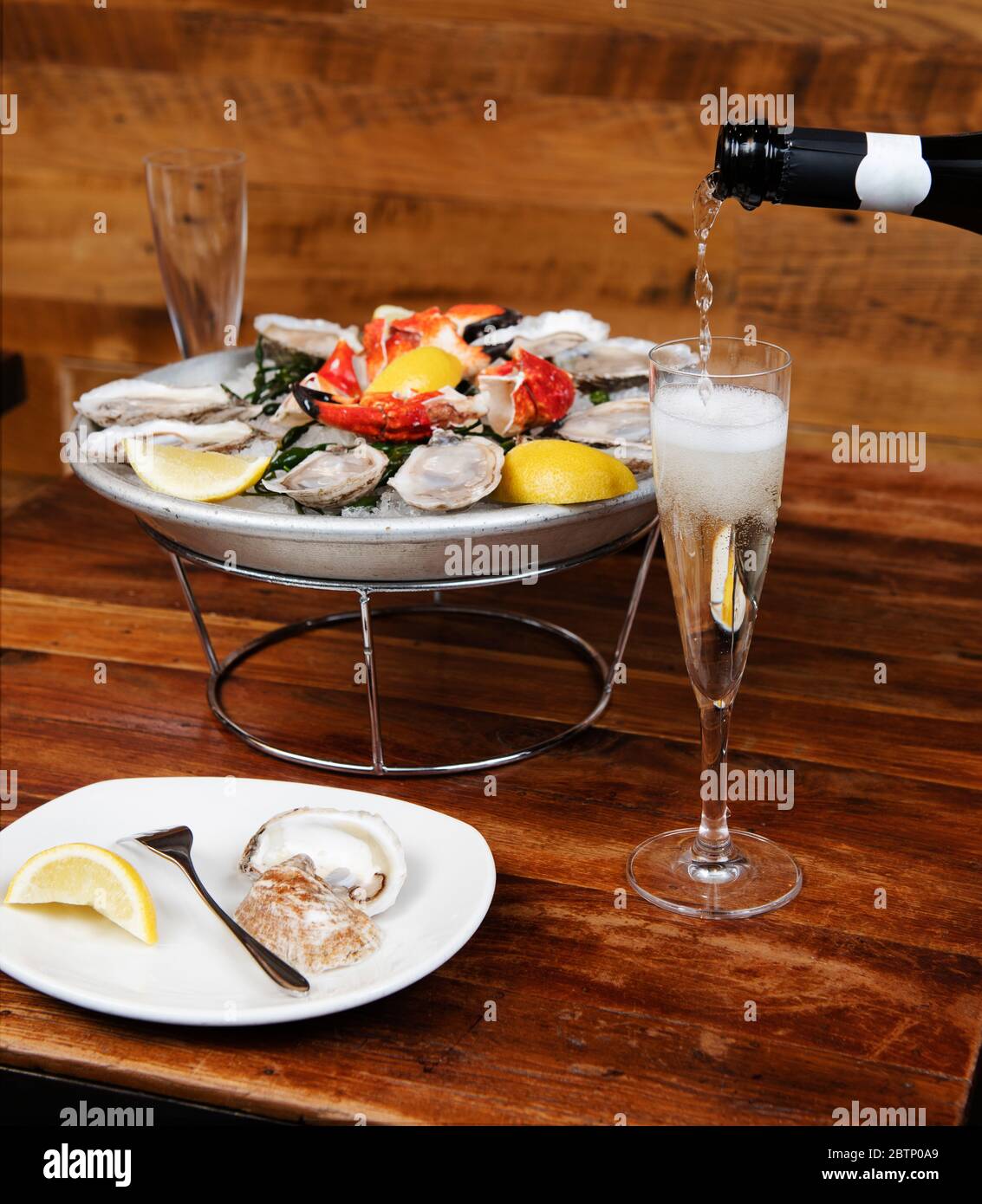 Piatto di pesce e champagne in fase di versamento Foto Stock