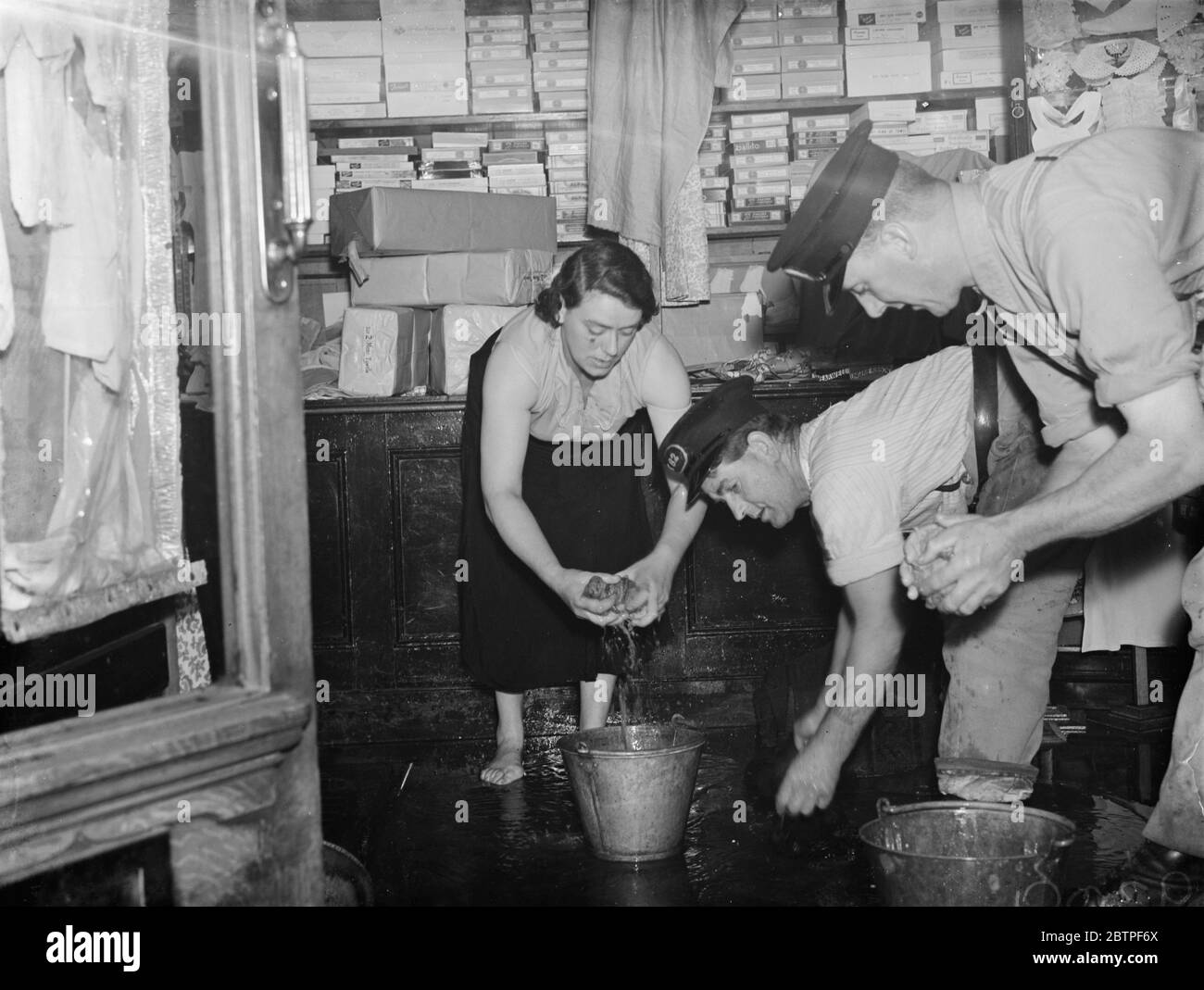 Burst Watermain a Plumstead . Sgombrare l'acqua dai negozi locali . 1938 Foto Stock