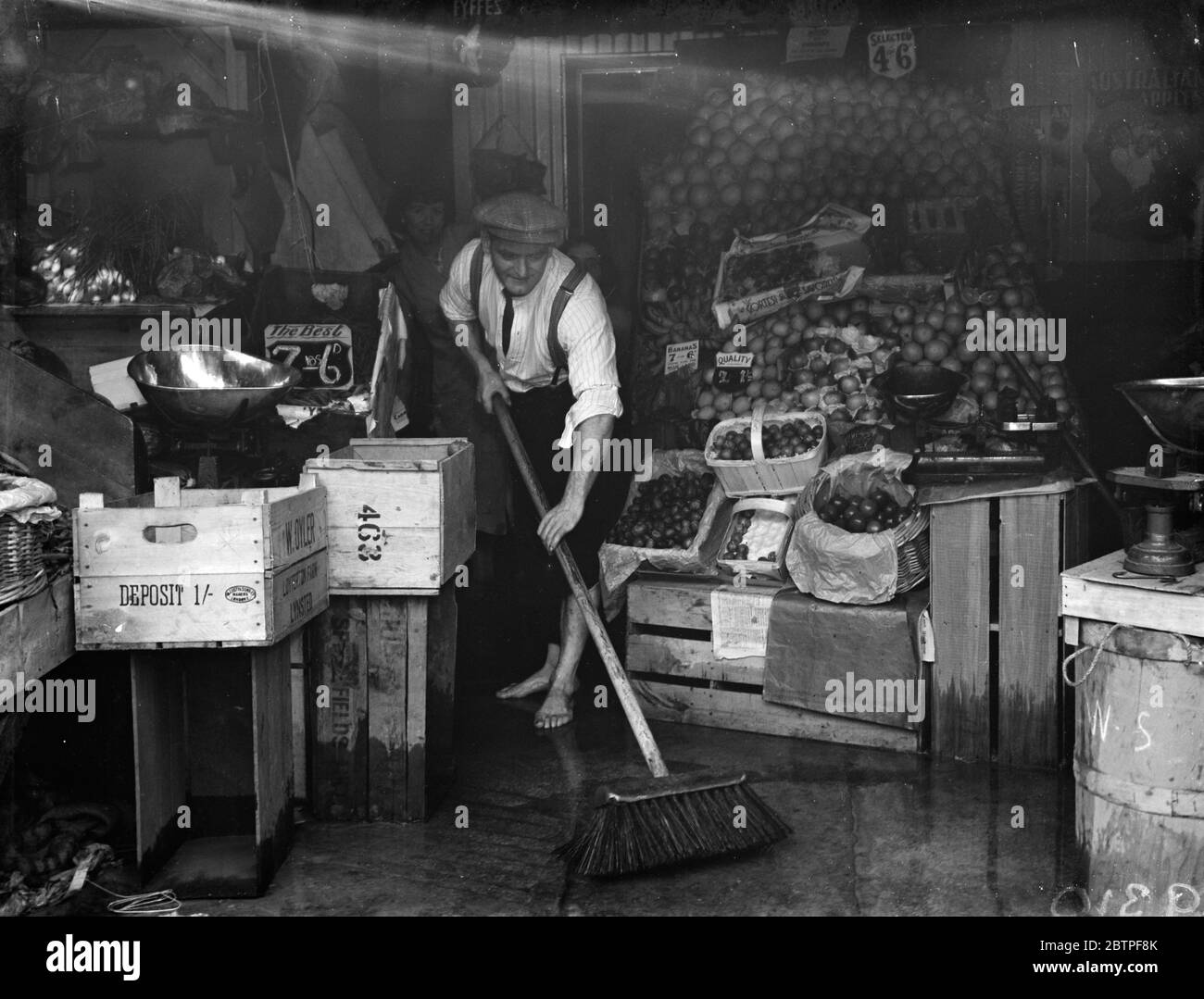 Burst Watermain a Plumstead . Sgombrare l'acqua dai negozi locali di greengrocer . 1938 Foto Stock