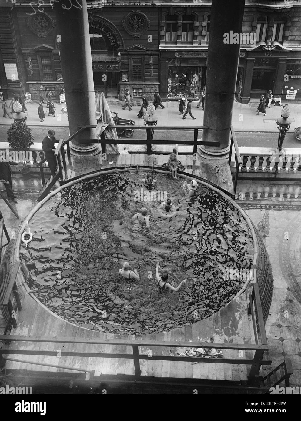 Bagni sopra il traffico Piccadilly . Una piscina è stata collocata sul balcone terrazzato dell'hotel Piccadilly e i bagnanti si tuffano nell'acqua appena sopra il traffico stradale. Bagnanti nella piscina sopra la strada. 3 agosto 1932 Foto Stock