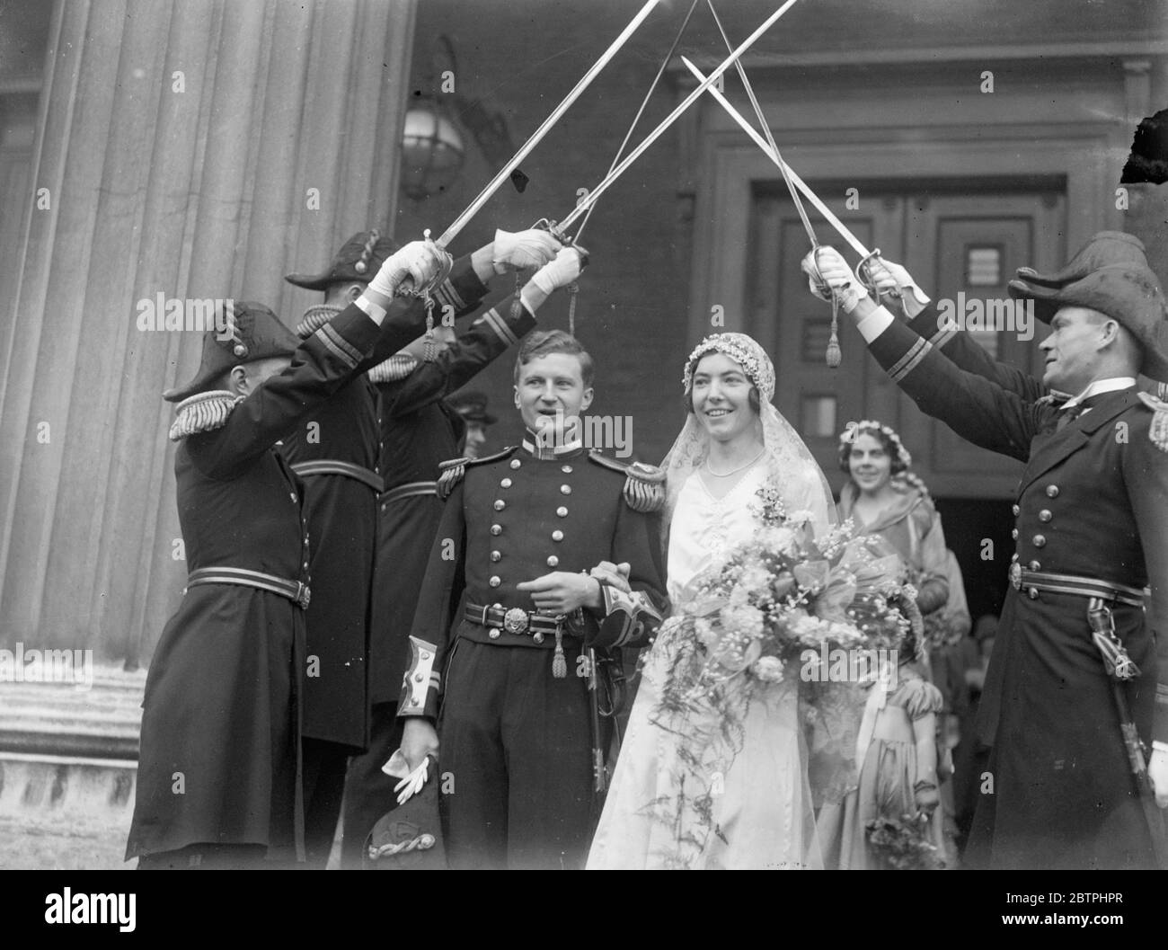 Matrimonio Navale grazioso. Il matrimonio di Lieut Henry Maitland , Kings Royal Navy e Miss Barbara Wells , si è svolto presso la Chiesa di San Pietro , Piazza Eaton , Lonodn . Lo sposo e lo sposo lasciano la chiesa sotto la guardia d'onore delle spade degli ufficiali navali . 15 febbraio 1932 Foto Stock