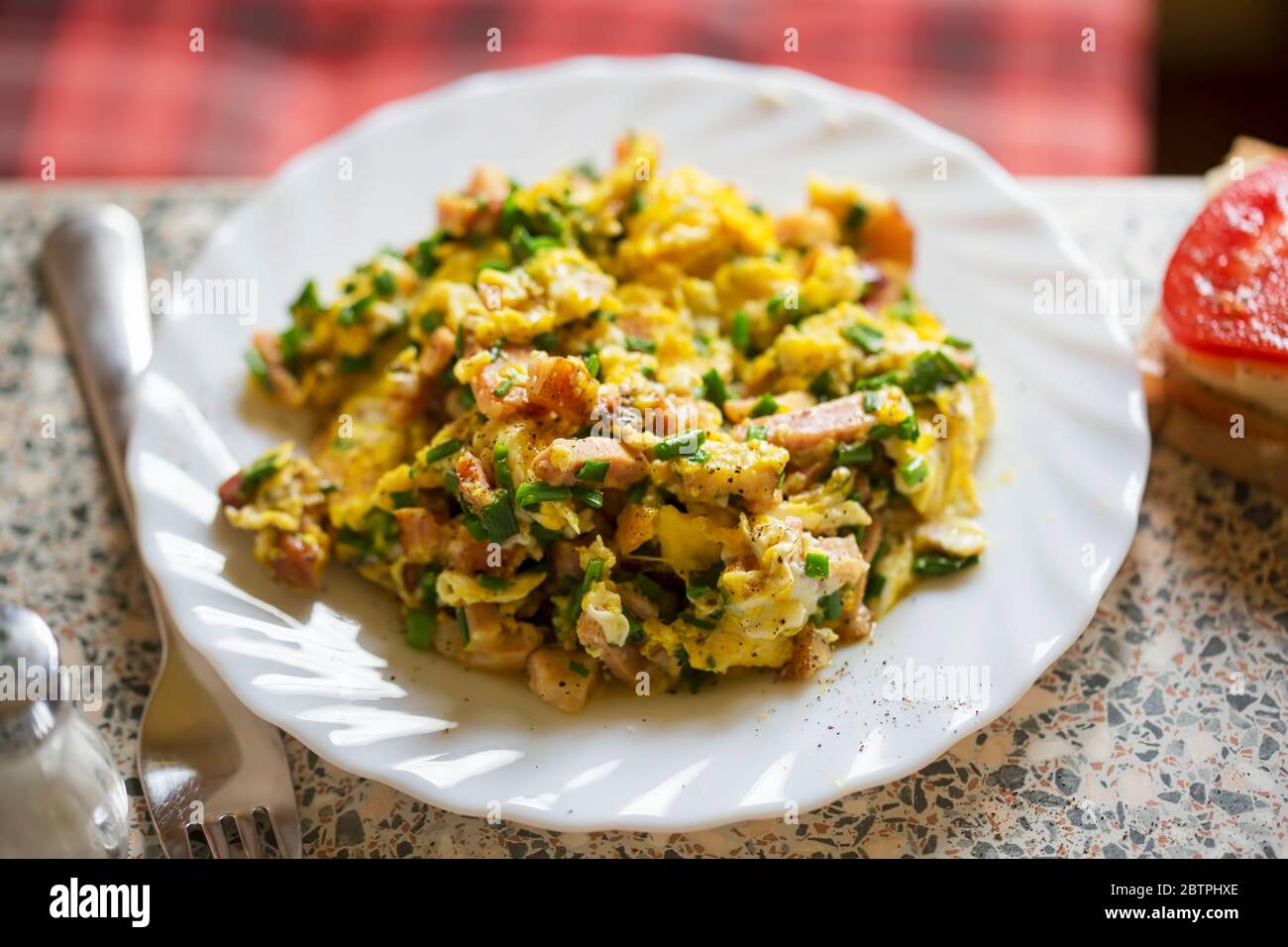 Uova strapazzate con pancetta, prosciutto, erba cipollina con formaggio a sandwich e pomodoro Foto Stock