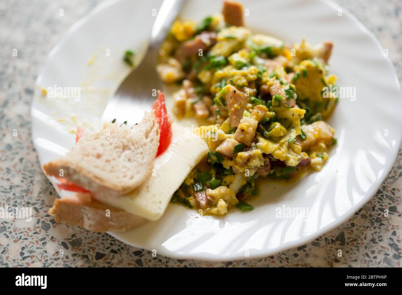 Uova strapazzate con pancetta, prosciutto, erba cipollina con formaggio a sandwich e pomodoro Foto Stock
