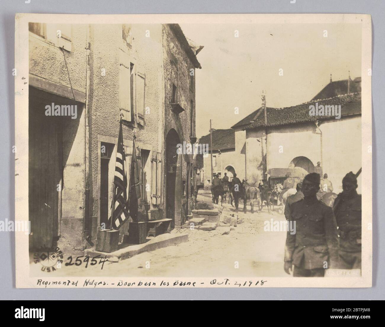 Regimental Hdqrs Bourbain les Baine 2 ottobre 1918. La bandiera americana e una bandiera reggimento sono apparsi fuori dal quartier generale regimentale. Ci sono due soldati in uniforme di fronte alla fotocamera nell'angolo inferiore destro della fotografia. Sullo sfondo ci sono soldati su cavalli che viaggiano lungo la strada. Foto Stock