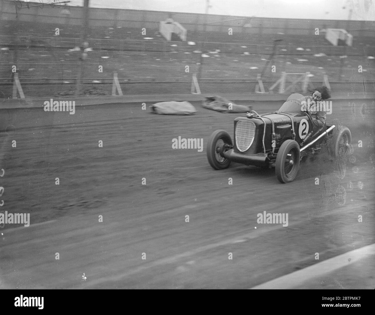 Sollevamento dei capelli . La donna driver prende su corsa di automobile di midget. Fay Taylor , noto pilota di corse e un tempo titolare del campionato femminile di speedway , sta ora prendendo parte alle corse automobilistiche di Midget . Lei gareggerà in tutto il paese . Foto mostra , i capelli di Fay Taylor che soffia nel vento mentre lei fa un giro di pista in una corsa di pratica al West Ham Stadium . 19 agosto 1936 Foto Stock