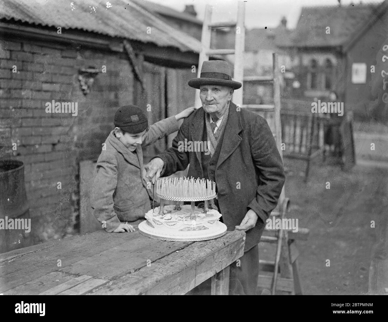 106 anni . Jimmy Miles , il famoso centenario di Southampton , celebra il suo compleanno nel 106 . Foto spettacoli , Jimmy Miles tagliando la sua torta di compleanno 106 guardato dal suo più giovane nipote . 17 marzo 1937 Foto Stock