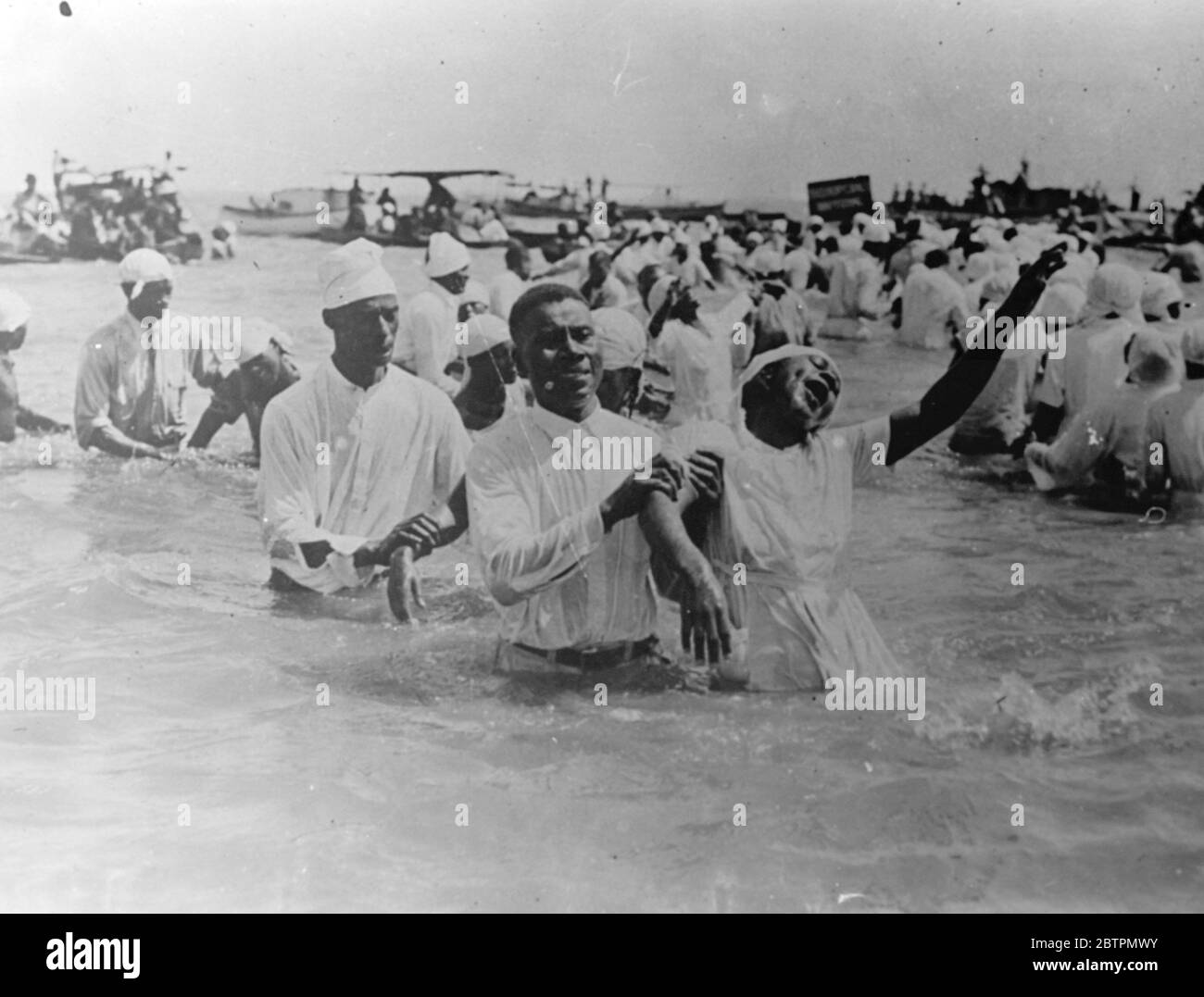 Didascalia originale: Cantare Hallelujah! Un candidato entusiasta, sotto forte stress emotivo, come altri 200, fu battezzato da Mons. Grace , Evangelista della Casa di preghiera a Newport News, Virginia. Il servizio battesimale, testimoniato da centinaia di persone, si è svolto nel porto di Newport News. 17 settembre 1936 Foto Stock