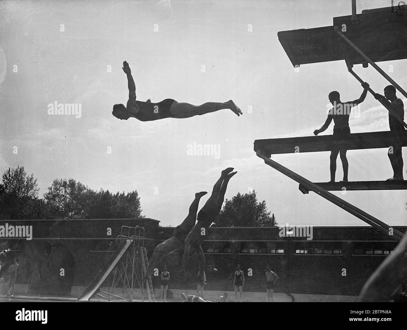 Silhouette a onda di calore. Con la sua silhouette contro il sole, un bagnino fa un'aggraziata immersione nelle fresche acque della piscina all'aperto del Victoria Park. 25 maggio 1937 Foto Stock