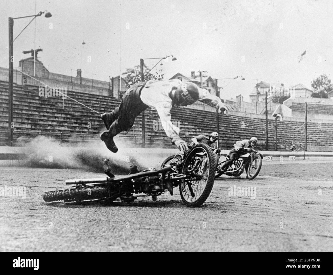 Fuoriuscita volante. Messo in pizzo la sua macchina in crash, Peewee Cullen, il pilota dell'American speedway, è stato catturato dalla telecamera l'istante prima di colpire i cadenti dopo una brutta fuoriuscita durante le esercitazioni allo Yankee Stadium di New York. I piloti sorpasso sono stati fortunatamente in grado di evitarlo e lui è sfuggito con un solo boccaglio di leganti e pochi lividi. Per ridurre il pericolo per i piloti caduti, in ogni angolo della pista di New York sono state installate luci rosse per avvertire gli altri concorrenti quando un uomo si schianta. 13 giugno 1937 Foto Stock