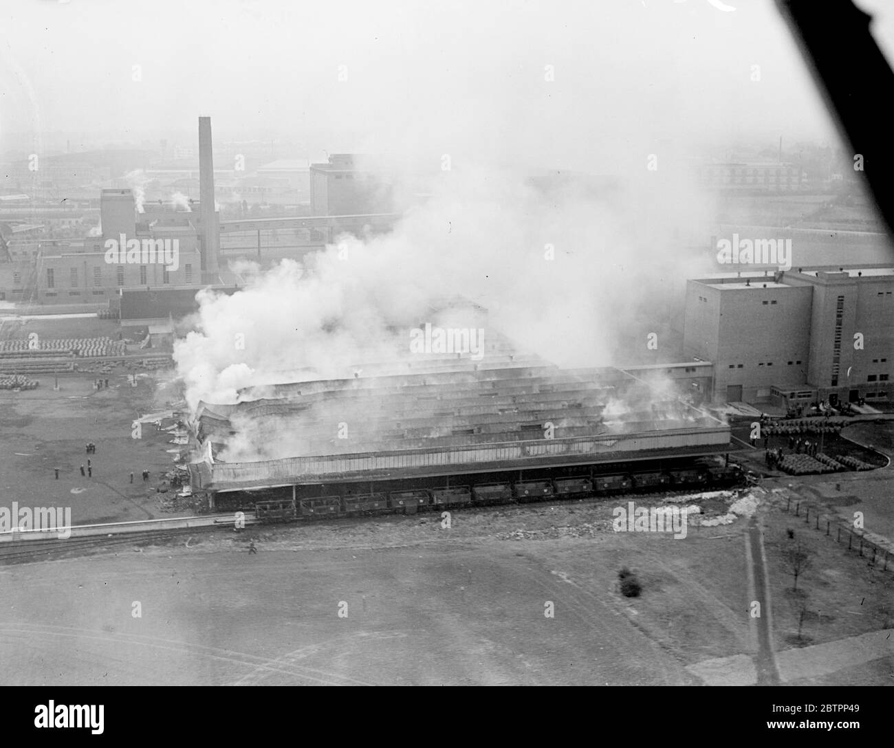 Park Royal Brewery una bizzarza. Un fuoco feroce infuriò per ore negli edifici della Guinness Brewery, Park Royal. La bera consumava la cooperativa e il garage, grandi annessi, anche se l'edificio principale era minacciato. Tre brigate, Willesden, Acton ed Ealing, combattevano le fiamme. La fabbrica di birra Guinness è stata completata verso la fine del 1935 ed è una delle più grandi di Londra. Spettacoli fotografici, una vista dall'aria degli edifici bruciati presso la fabbrica di birra Guinness. 5 agosto 1938 Foto Stock