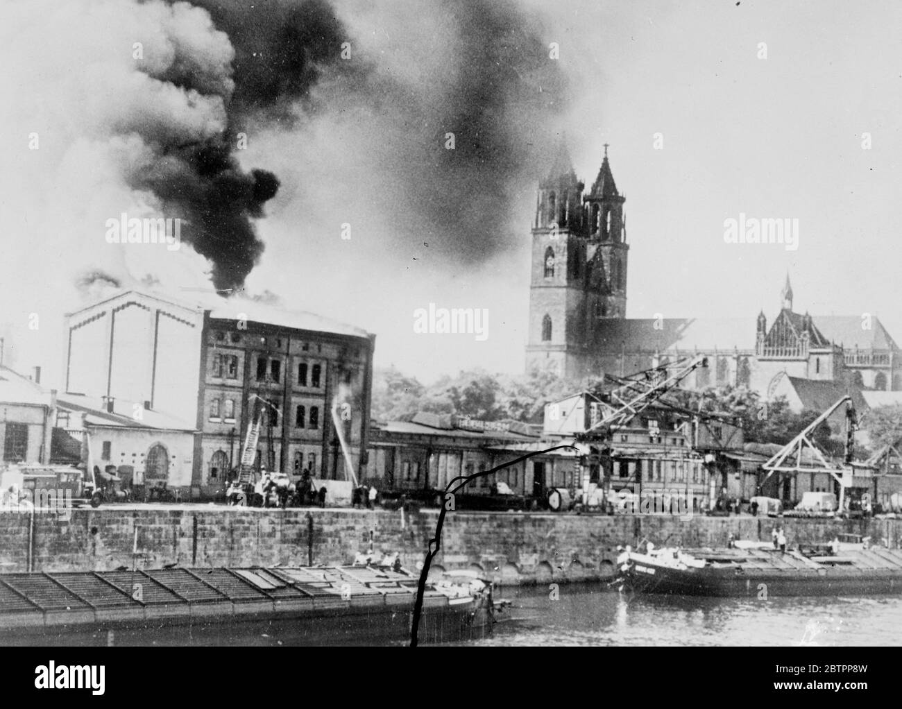 Il magazzino di cacao si trova a Magdeburgo. Vicino alla famosa cattedrale. A pochi metri dalla famosa cattedrale di Gothus, un deposito di cacao e di olio è stato quasi completamente distrutto da un incendio sulle rive del fiume Elba a Magdeburgo, in Sassonia. Le brigate sono state chiamate da tutte le parti della città per affrontare l'epidemia, ma nonostante i loro sforzi diverse centinaia di tonnellate di cacao sono state distrutte. Foto, fiamme e fumo che saltano dal tetto del magazzino in fiamme mentre i vigili del fuoco combattono la colpe. 9 luglio 1938 Foto Stock