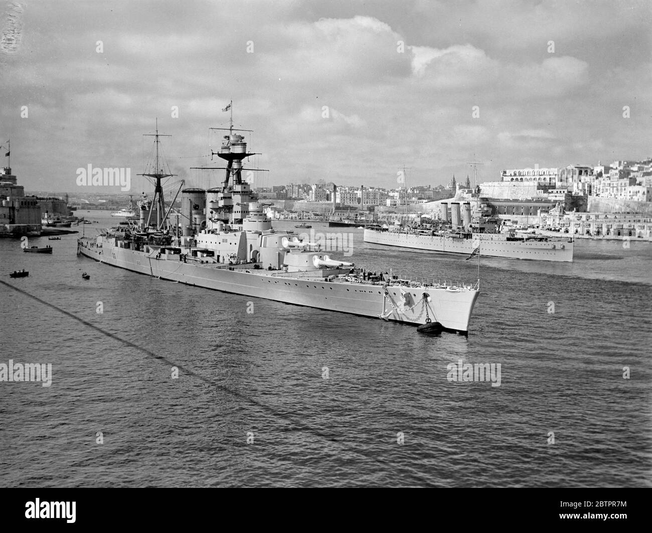 La nave da guerra più grande del mondo a Malta. HMS Hood, la più grande nave da guerra del mondo ancora nel porto di Valletta, capitale di Malta, dove le navi della Marina britannica massacrarono prima di partire per gli esercizi combinati della flotta Home e Mediterranea, trasferiti nell'Atlantico meridionale, a causa del pericolo nelle acque spagnole. Dietro 'Hood' si trova la città di la Valletta, che contiene molte reliquie dell'occupazione degli antichi Cavalieri di Malta. Questa foto è stata presa da 'HMS coraggioso' mentre la portaerei stava entrando nel porto. 5 marzo 1937 Foto Stock