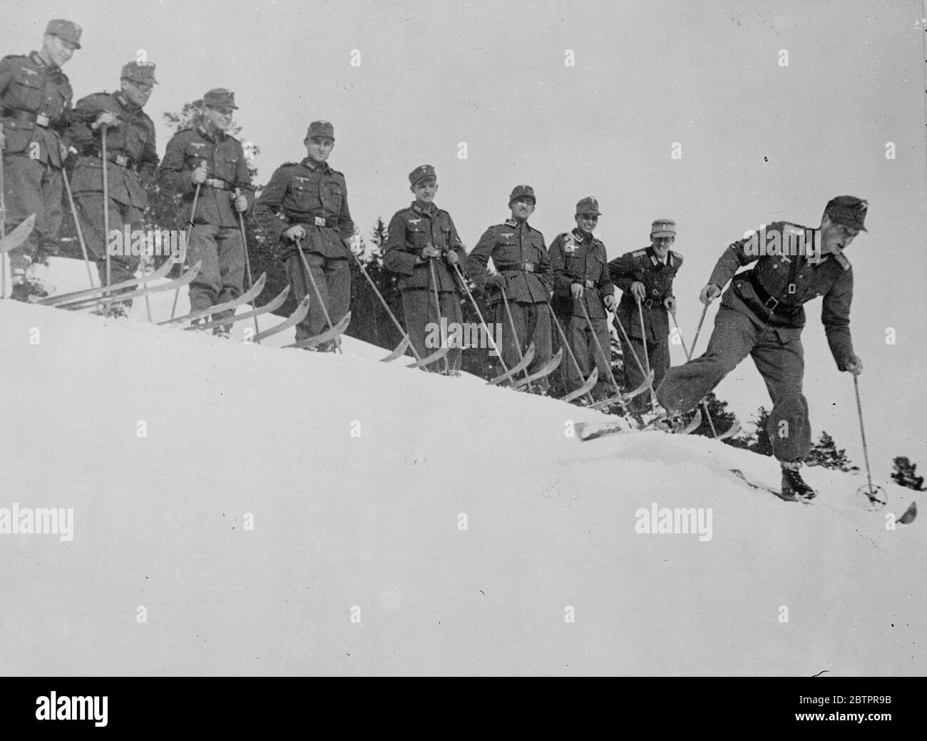 Comando perfetto!. La squadra di sci del 19° Reggimento montano dell'esercito tedesco, che guarda una dimostrazione del leader Sommer durante l'allenamento, nei pressi di Mitterwald per i Campionati di sci dell'esercito tedesco che si svolgono il mese prossimo. 18 gennaio 1938 Foto Stock