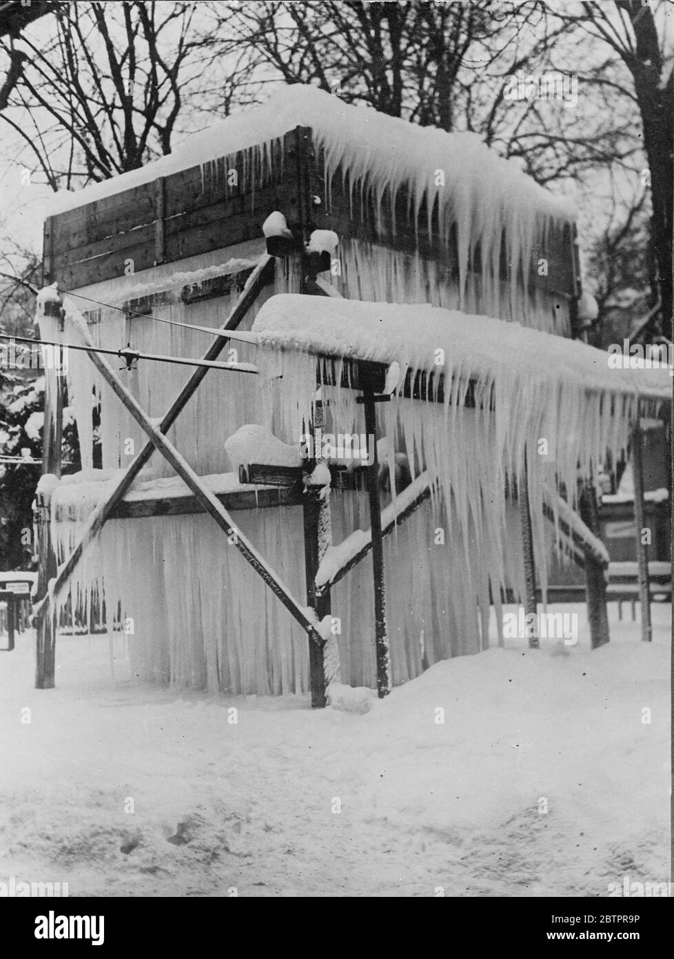 Tempio di ghiaccio. Le cicette sospese dal tetto a terra rendono questa capanna di legno quasi bella in un villaggio dell'Austria, ora vivendo uno dei peggiori inverni in archivio. 12 gennaio 1938 Foto Stock