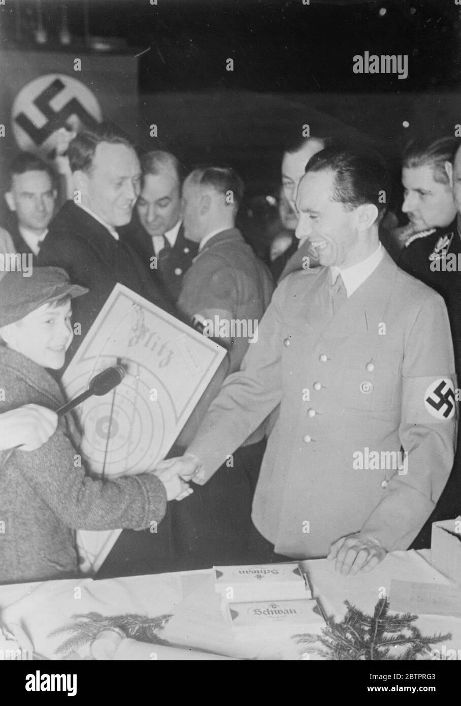 Dr Goebbel'-Babbo Natale. Il Dr. Goebbels, Ministro della Propaganda nazista, sorride ampiamente mentre scuote le mani con un giovane ospite dopo aver presentato un regalo di Natale a Berlino. I regali sono stati distribuiti a 150,000 bambini a Berlino nel quadro della campagna di aiuto invernale. 25 dicembre 1937 Foto Stock