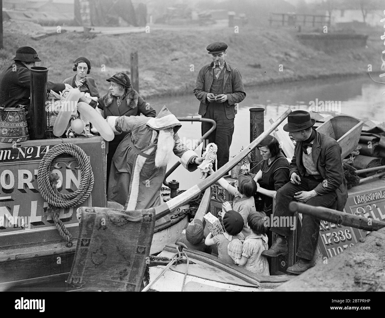 Santa va dall'acqua. Distribuisci i giocattoli per uscire dai bambini. Padre Natale è venuto in barca per pagare la sua visita annuale a Brentford (Middlesex) e ha distribuito doni ai bambini dei barcaioli che erano venuti in particolare da tutti i corsi d'acqua britannici per l'occasione. Santa era il signor Harry Wall, missionario del canale boatman's Institute. Mostre fotografiche, Babbo Natale, distribuendo i suoi doni alla lattina i nostri figli, Brentford, Middlesex. 22 dicembre 1937 Foto Stock