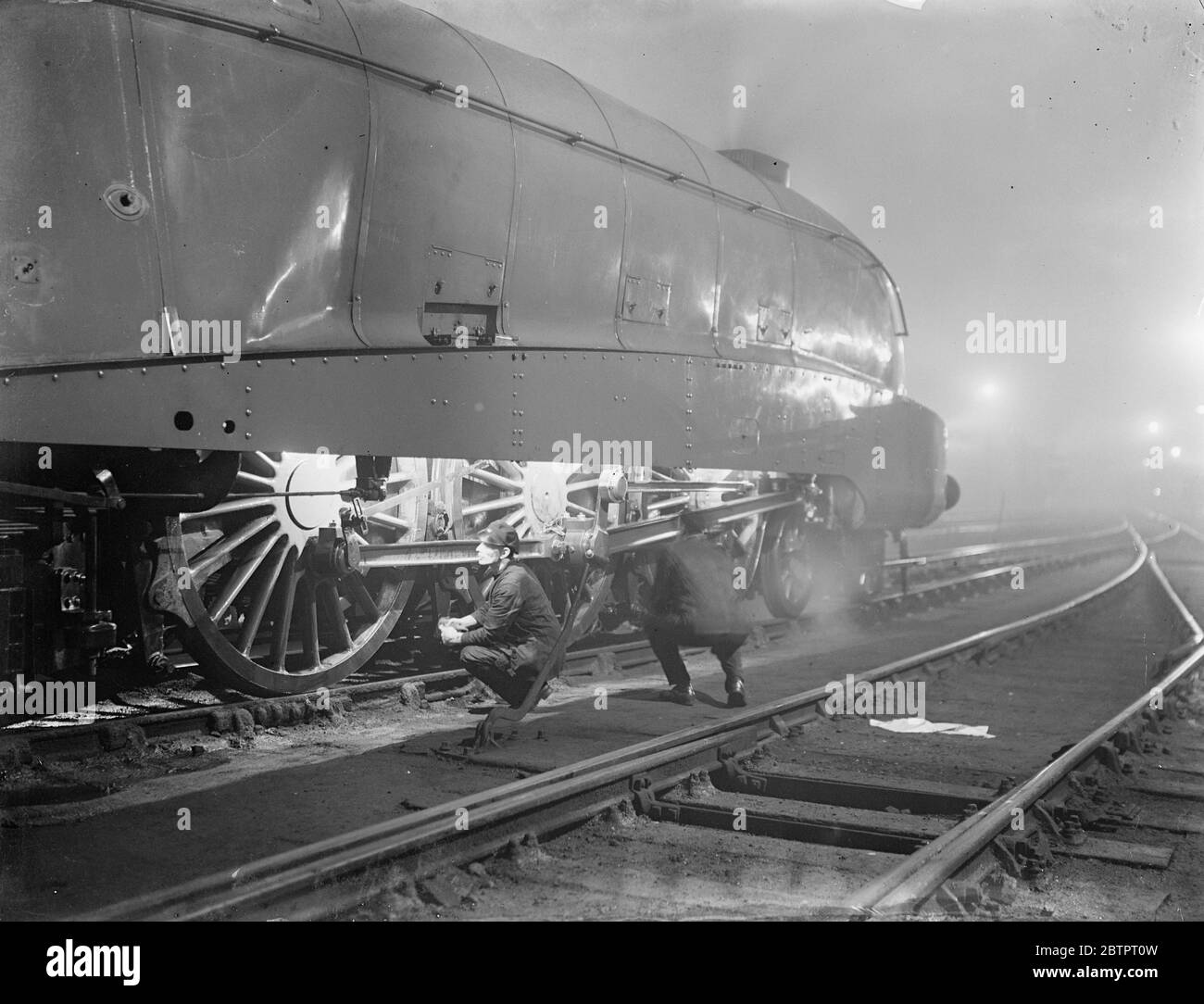 Alimentazione sotto i proiettori. Le locomotive britanniche usano per la prima volta la luce elettrica. Per la prima volta il petrolio è stato soppiantato dall'elettricità per le lampade dei locomotori britannici. La gigantesca locomotiva snellita '10,000' di Londra e della ferrovia del Nord Est che trasporta, la Londra, Newcastle express, ha luci illuminate da elettricità e le enormi ruote motrici e le bielle di proiettore per rendere l'ispezione delle parti in movimento più facile mostra foto, l'alluvione illuminato '10,000'. Poco prima di lasciare King's Cross sulla sua corsa notturna a Newcastle. 26 novembre 1937 Foto Stock