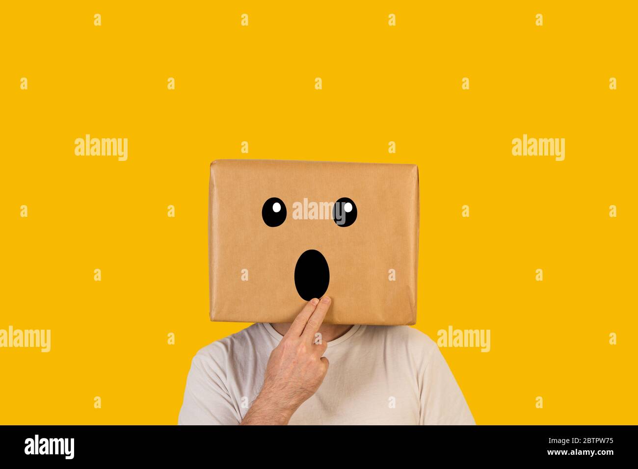 Uomo con la testa in una scatola e gesto di stupore su sfondo giallo Foto Stock