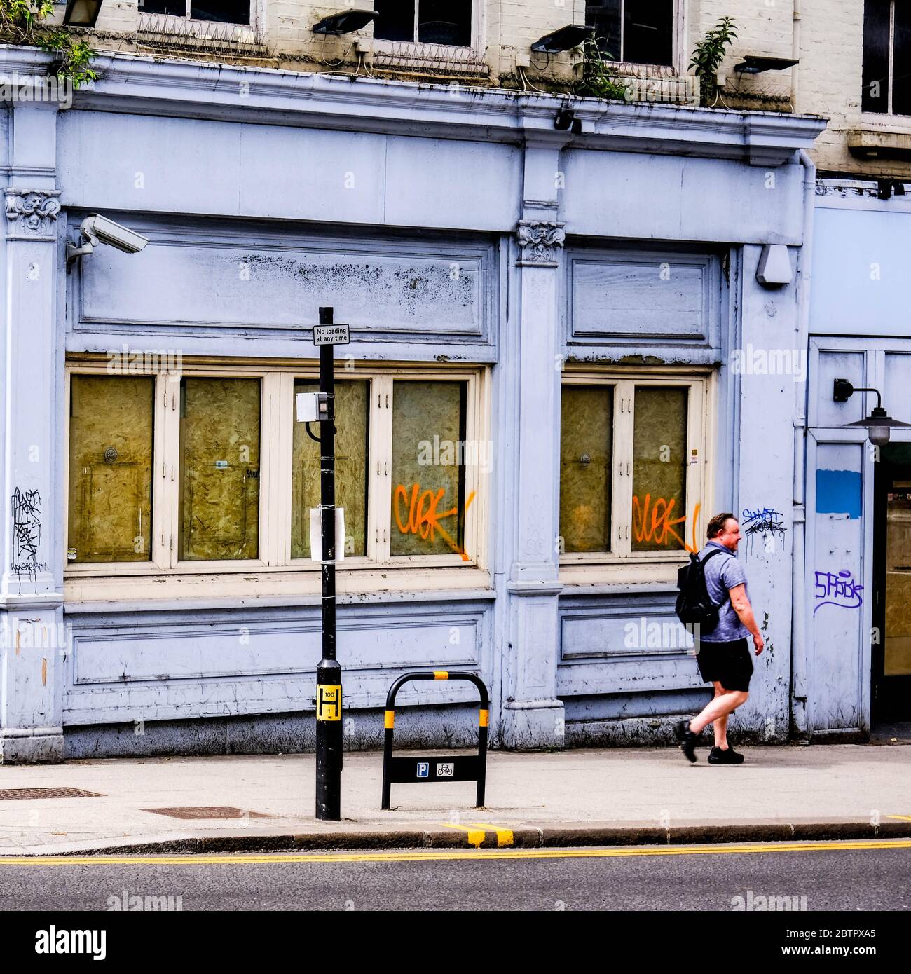 Man Walking di fronte A un pub chiuso o a una pubblica casa con le sue finestre salite a South London, UK Foto Stock