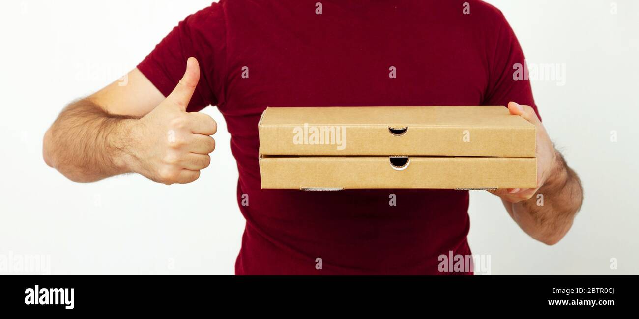 Consegna uomo in rosso t-short che tiene scatole di cartone di pizza su sfondo bianco. Consegna pizza. Consegna a domicilio del corriere. Cibo ordinare scatole della pizza Foto Stock