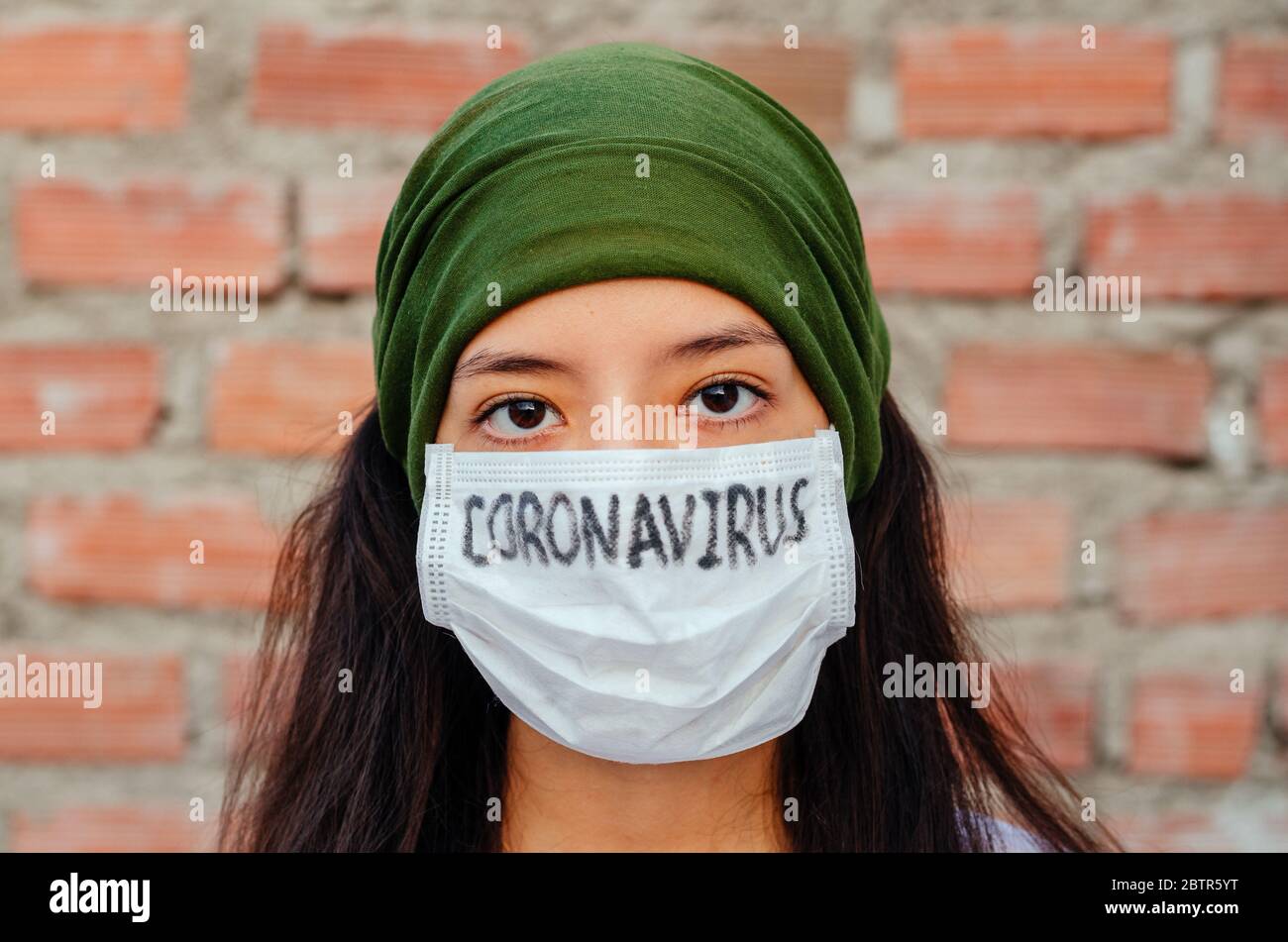 Ragazza con maschera per proteggersi dal Coronavirus. Covid-19 pandemico. Coronavirus scritto in maschera Foto Stock