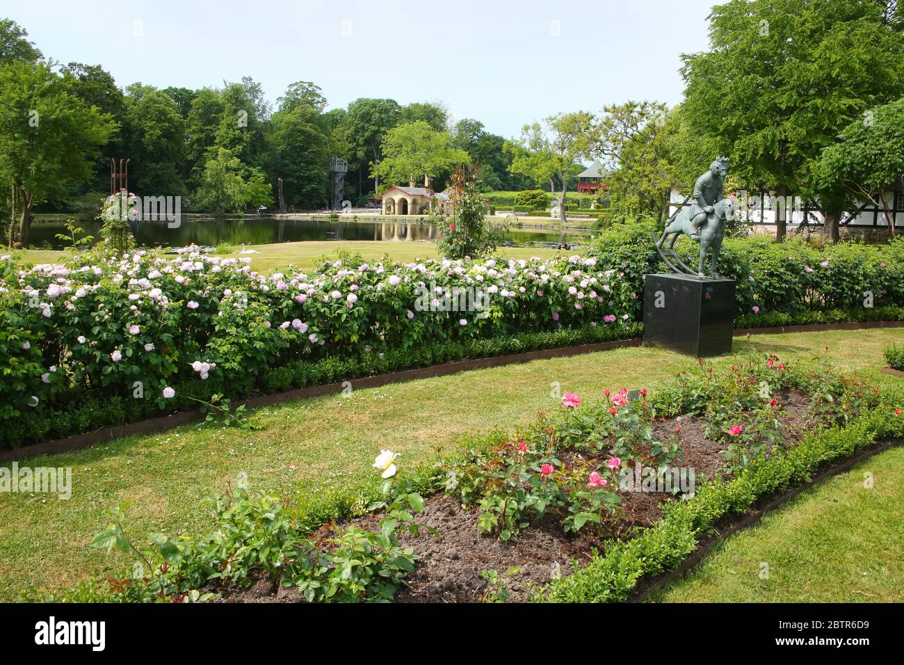 Tradizionale giardino pubblico formale, in fiore in estate con un lago sullo sfondo, situato vicino Kvaerndrup, isola di Funen, Danimarca. Foto Stock