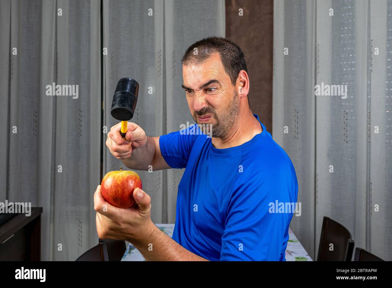 Uomo con i capelli corti in t-shirt blu che regge una mela. Concetto di vita sana Foto Stock