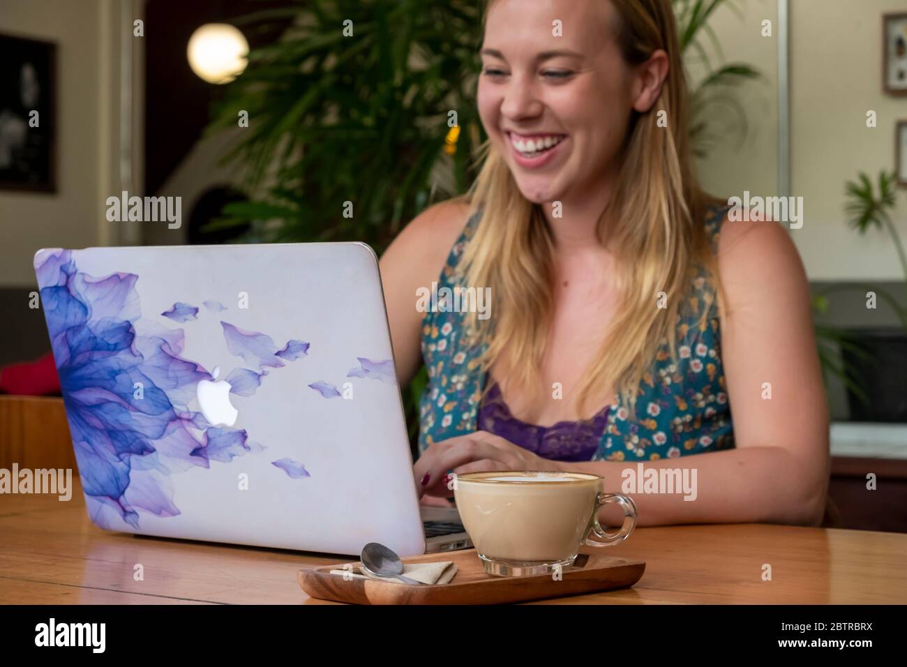 Una donna che lavora su un computer portatile, con una tazza di caffè in un ufficio domestico o in un caffè Foto Stock