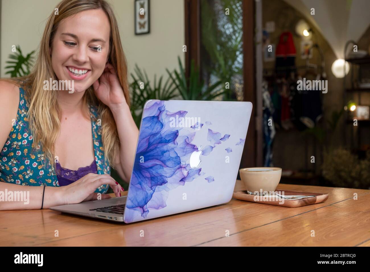 Una donna che lavora su un computer portatile, con una tazza di caffè in un ufficio domestico o in un caffè Foto Stock