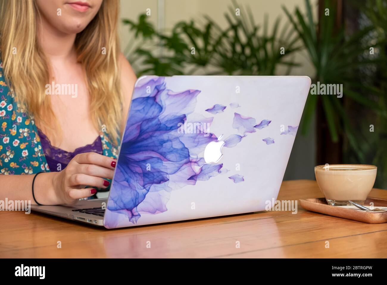 Una donna che lavora su un computer portatile, con una tazza di caffè in un ufficio domestico o in un caffè Foto Stock