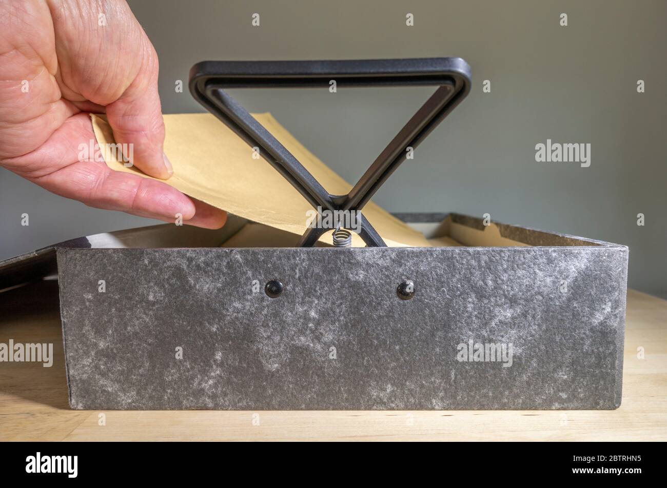 Una mano dell'uomo con coperchio della lima della scatola aperto e fermo a molla sollevato, sostituendo o togliendo un documento. Foto Stock