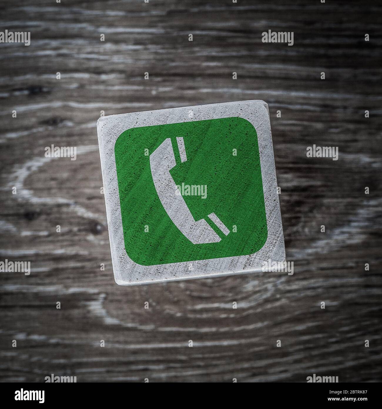 Un cartello verde del telefono o del telefono cellulare, simbolo o icona che indica la connessione e risponde su un blocco di legno con sfondo di legno e spazio per la copia Foto Stock