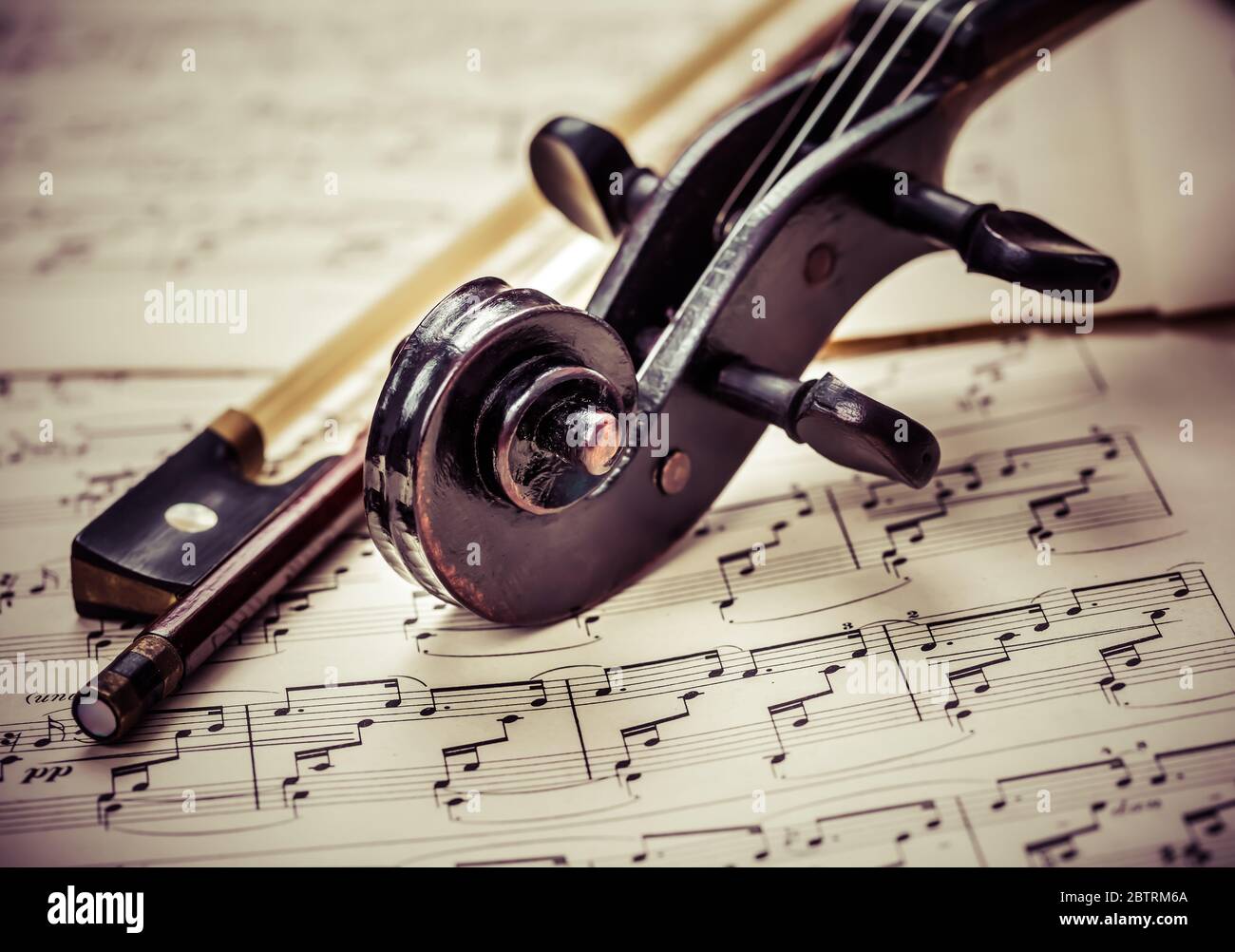 Dettaglio del vecchio violino con fiddlestick sulle note musicali in un look vintage Foto Stock