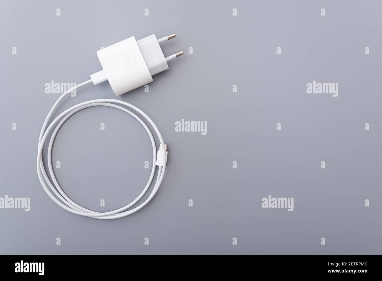 Caricabatterie adattatore bianco con cavo di ricarica usb su superficie grigia, vista dall'alto Foto Stock