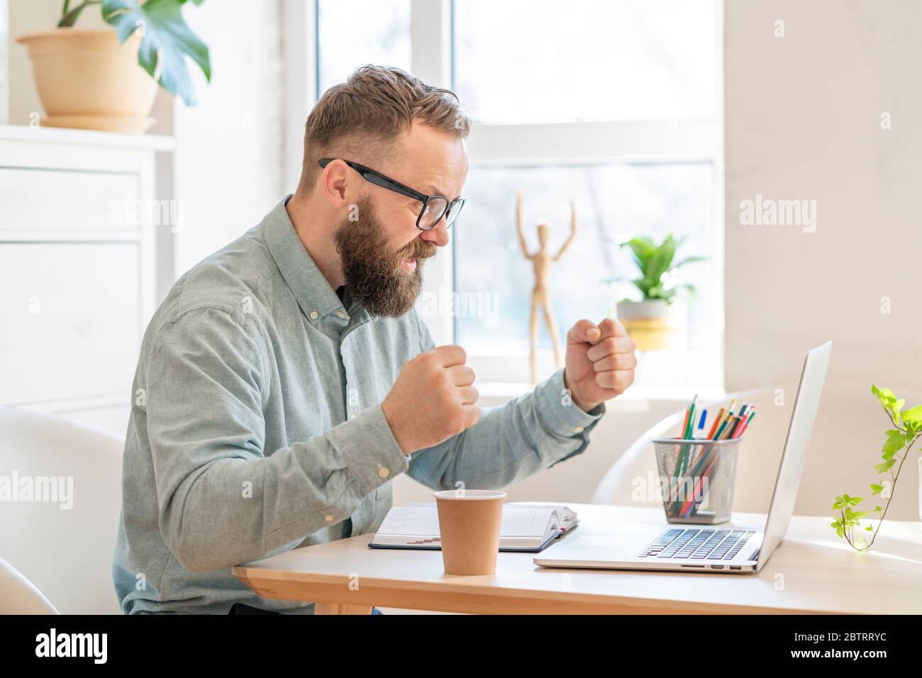 Felice uomo d'affari sentire l'eccitazione, alzando pugni, guardando il notebook ricevere buone notizie, raggiungere gli obiettivi di vita, celebrare il successo aziendale, fare un gesto vincitore. Concetto di successo e raggiungimento degli obiettivi. Foto Stock