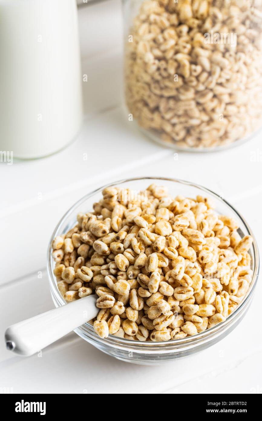 Grano soffiato coperto di miele in una ciotola di vetro. Colazione a base di cereali su un tavolo da cucina. Foto Stock