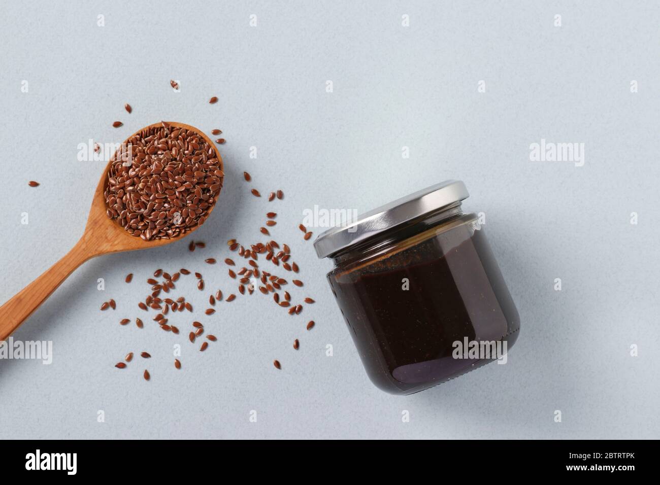 Pasta organica vegana di semi di lino in vaso di vetro e semi di lino in cucchiaio su sfondo azzurro, urbach, prodotti alimentari sani, vista dall'alto Foto Stock