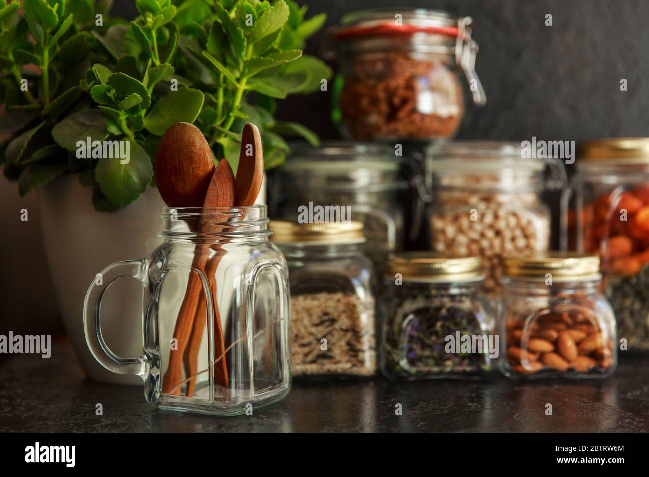 Set per alimenti. Cereali crudi, pasta, semole, legumi biologici e semi utili in vasi di vetro. Fonte vegana di proteine e risorse energetiche. Stoccaggio di alimenti in vasetti di vetro, shopping ecologico, su sfondo scuro, concetto di stoccaggio rifiuti zero, riciclaggio, concetto di stile di vita sostenibile Foto Stock