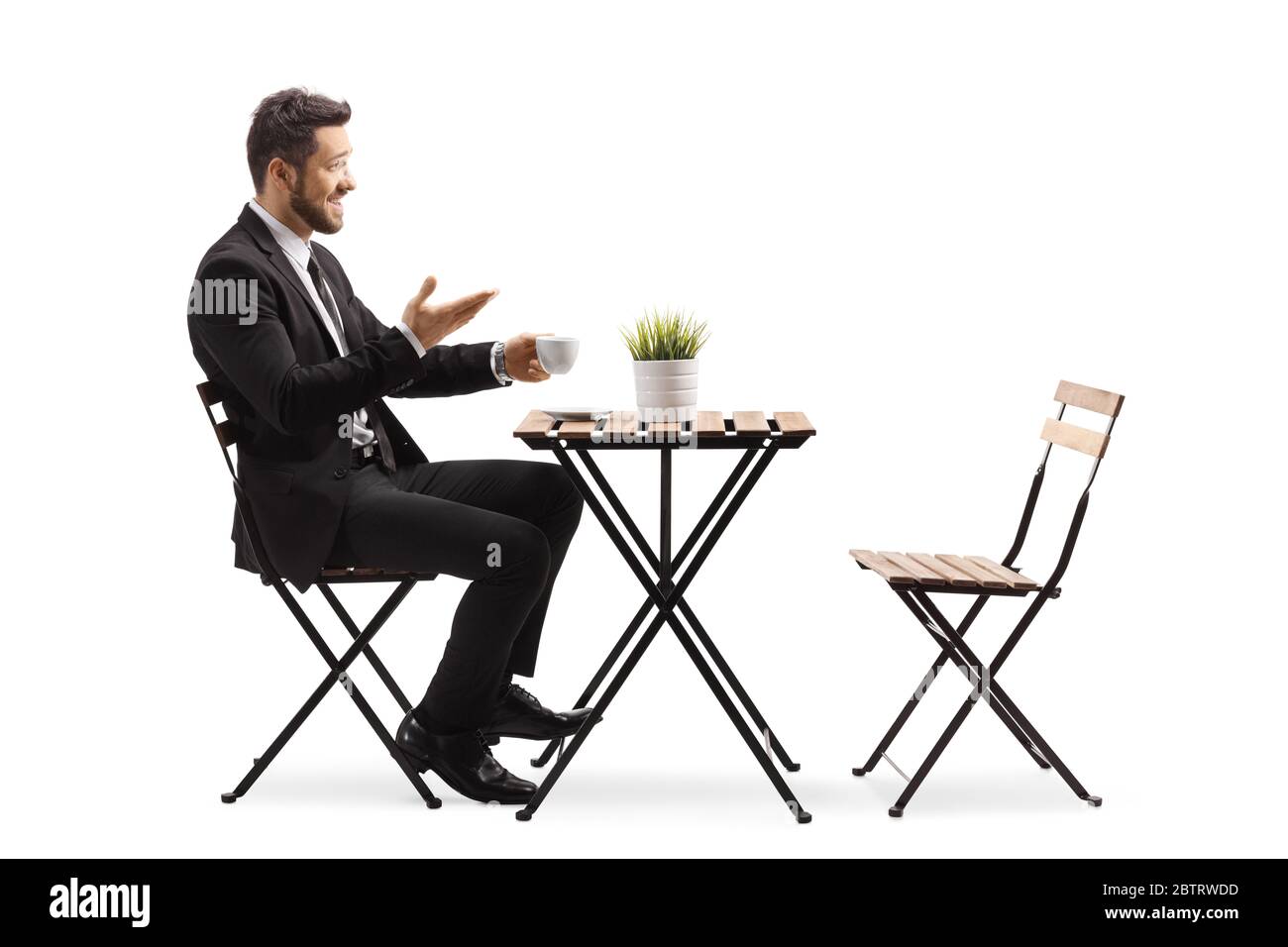 Giovane uomo in tuta e cravatta seduto in un caffè e bere caffè isolato su sfondo bianco Foto Stock