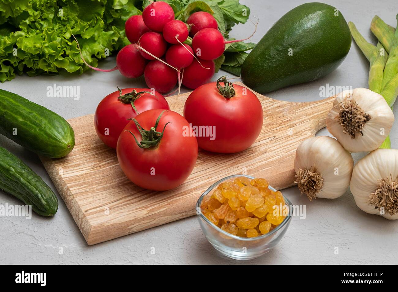 Fondo vegetale con alimenti alcalini: Uva passa, avocado, pomodori, cetrioli, lattuga, aglio, rafano Foto Stock
