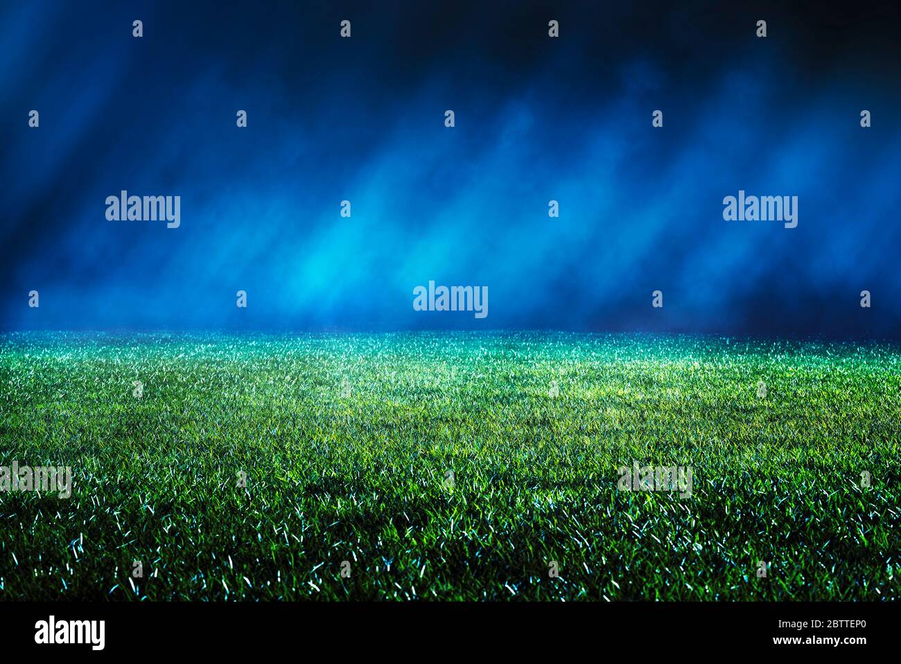 Vista sul prato mantenuto allo stadio di calcio. Raggi di luce che si illuminano verso la nebbia in direzione diagonale. Vista notturna bassa con effetti di luce... Foto Stock