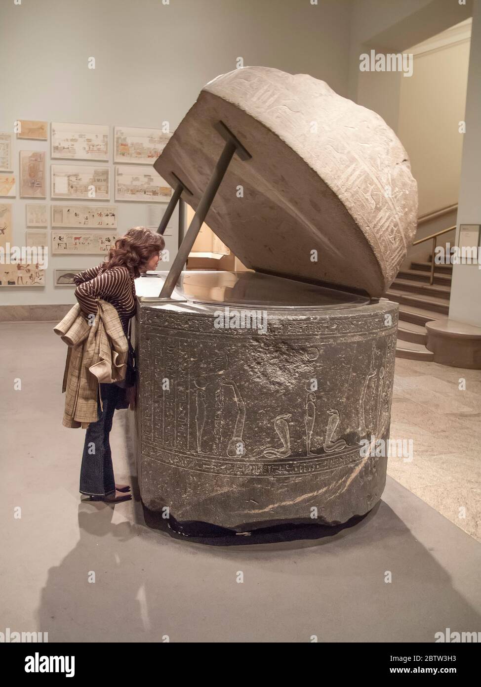 Donna che guarda all'interno di un antico sarcofago egiziano nel Metropolitan Museum of Art, New York, USA Foto Stock