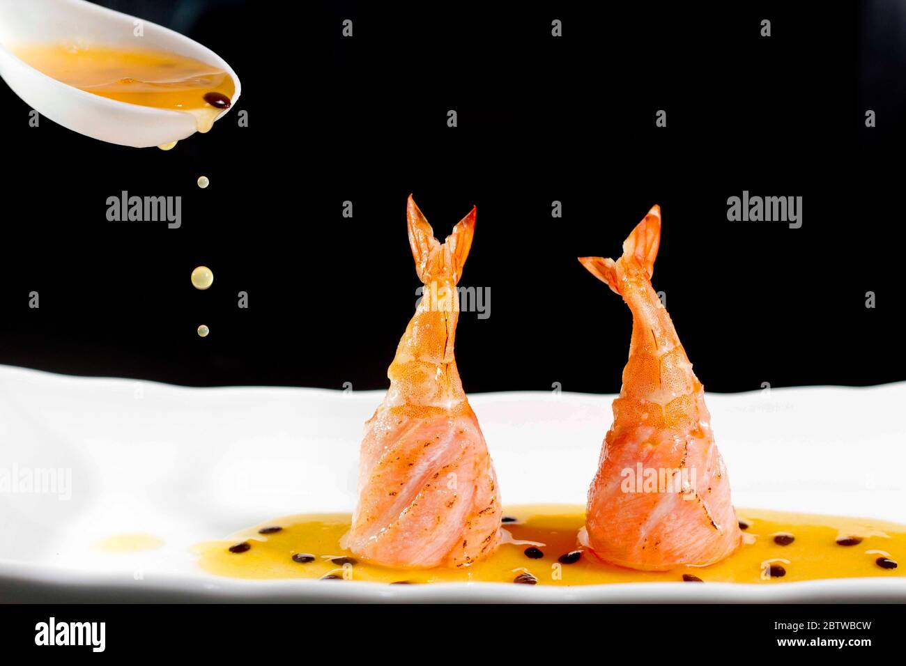 Salmone e gamberi cibo giapponese, con salsa di frutta passione gocce belle. Cucina asiatica, fusion orientale distinta servita su piatto bianco, scuro Foto Stock